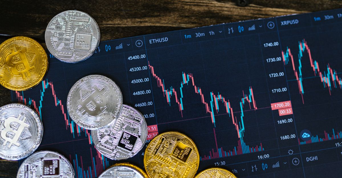 Close-up of gold and silver cryptocurrency coins on a digital trading chart.